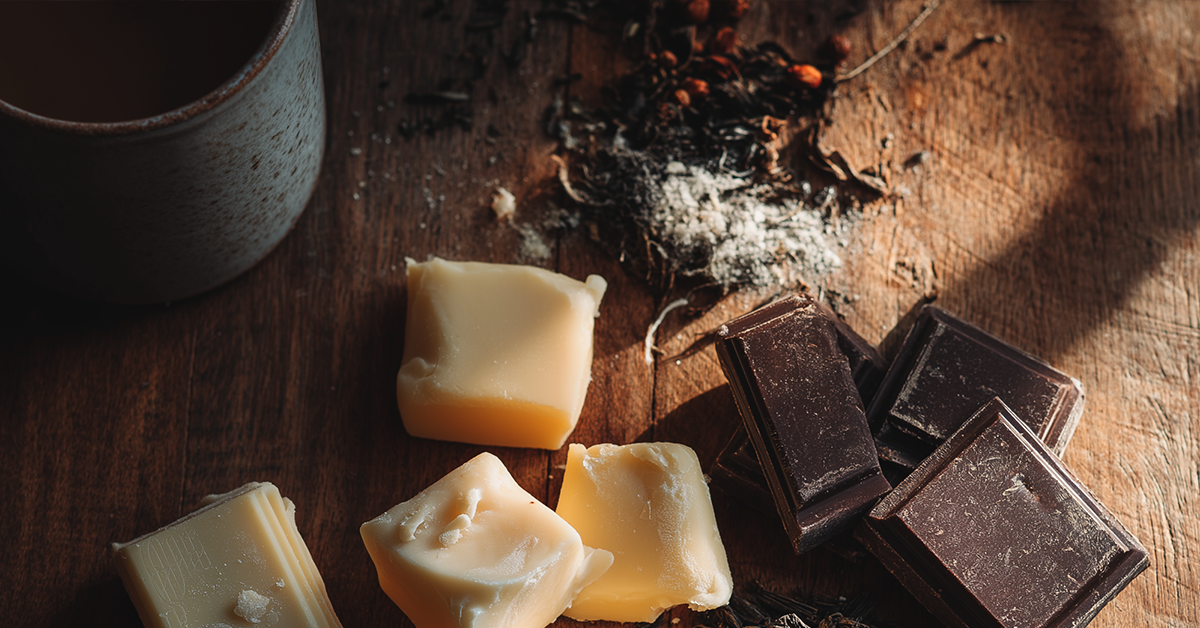 Ingrediënten voor een Valentijnsdag proeverij: chocoladeblokjes en losse theebladeren op houten tafel